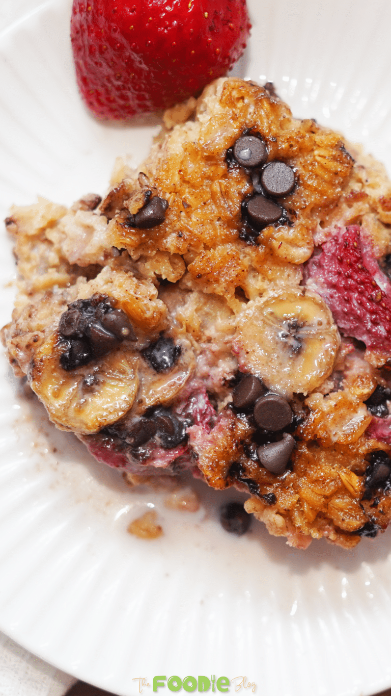 Close-up of baked oatmeal with banana slices, strawberries, and chocolate chips on a white plate