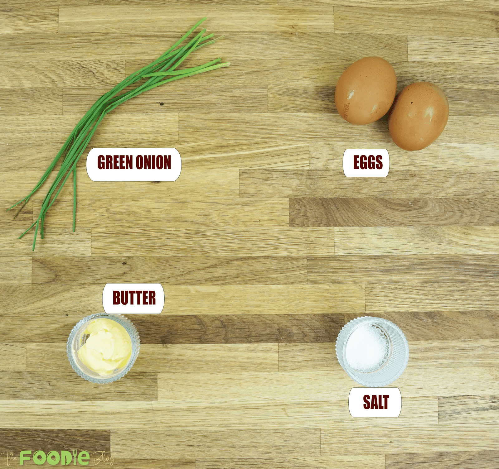 Overhead view of eggs, butter, salt, and green onion or chives for making a French omelette