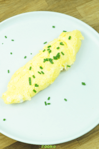 Soft French omelette served on a plate and topped with chopped chives