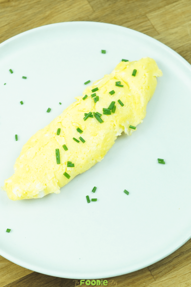 Soft French omelette served on a plate and topped with chopped chives