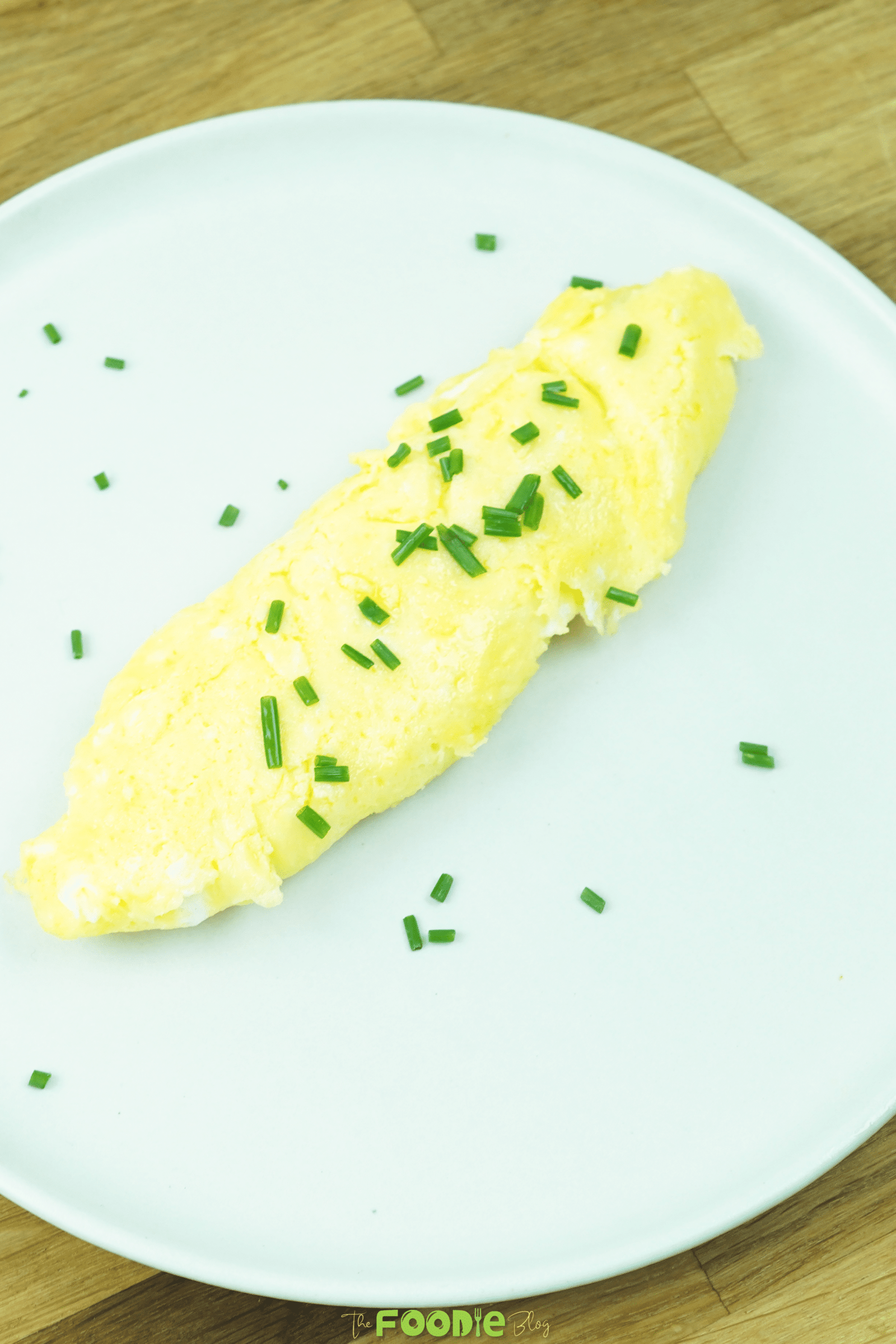 Soft French omelette served on a plate and topped with chopped chives