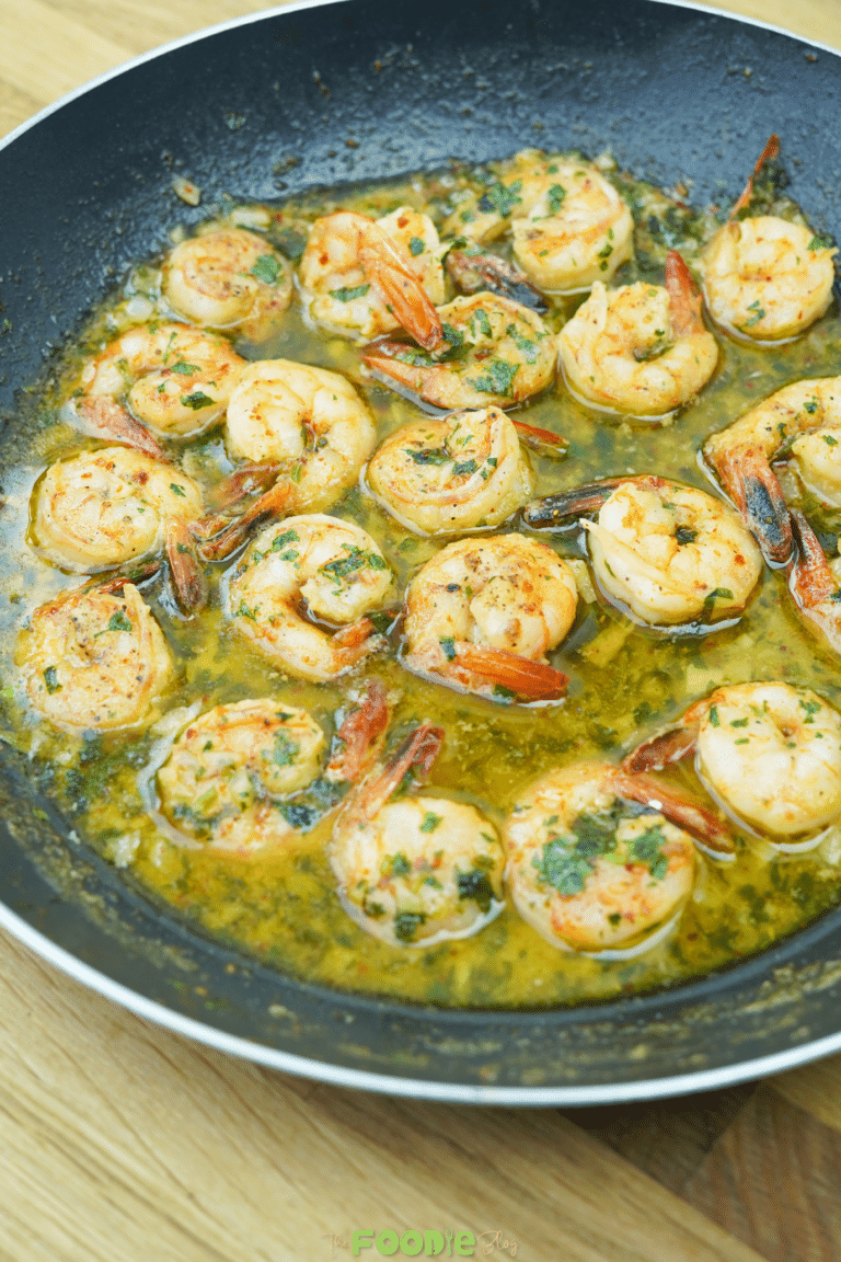 Close-up of shrimp in garlic butter and white wine sauce with chopped parsley in a skillet