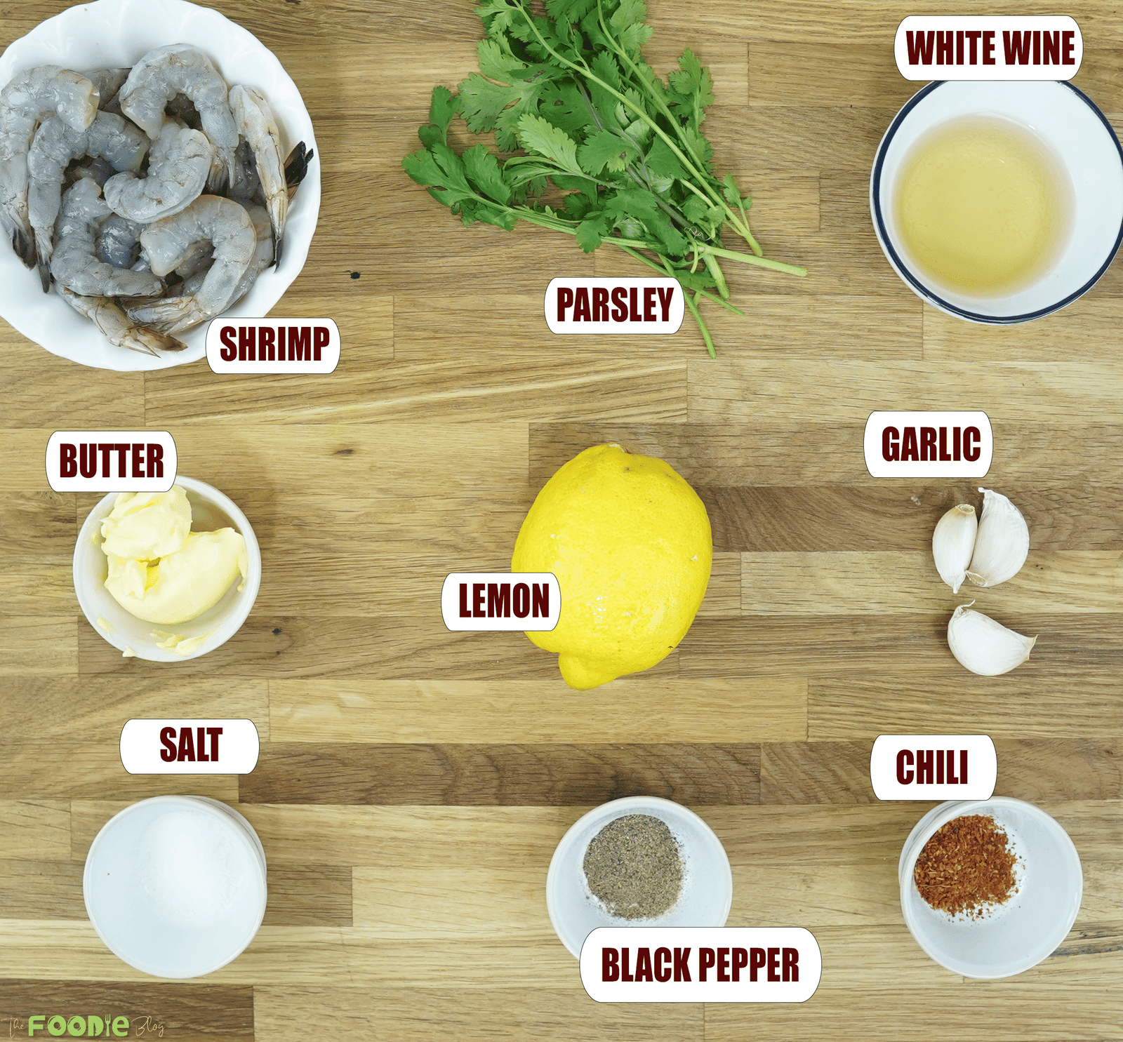 Overhead view of shrimp, butter, parsley, lemon, garlic, white wine, salt, black pepper, and chili flakes for garlic butter white wine shrimp recipe