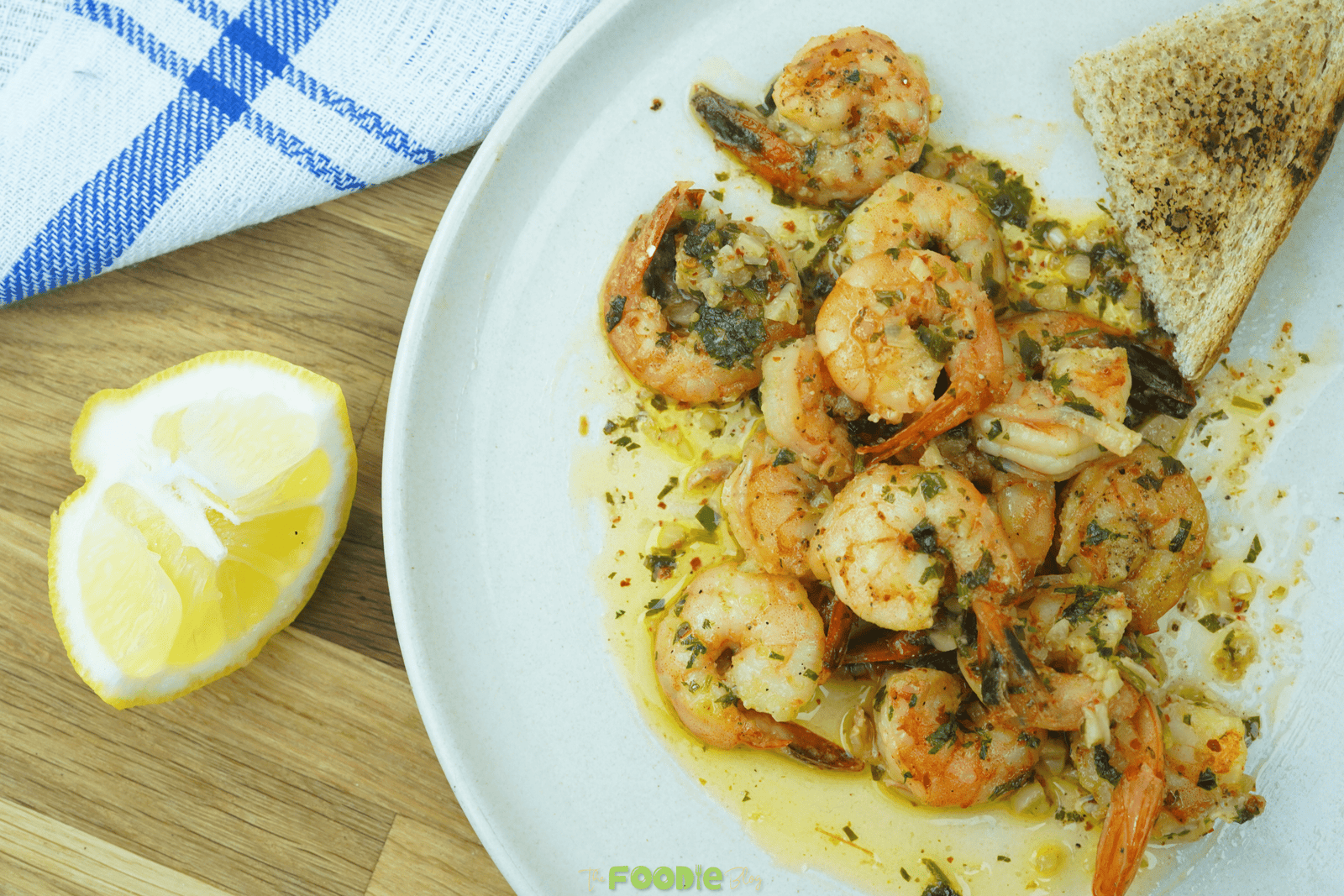 Garlic butter white wine shrimp served in a bowl with toasted bread and a lemon wedge on the side