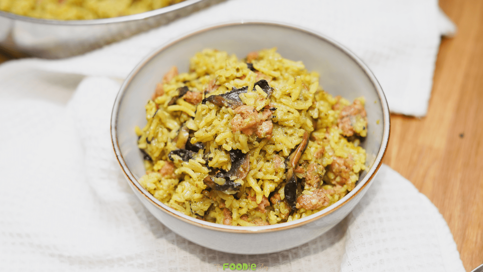 Ground turkey casserole served in a bowl on a white towel with the casserole pan blurred in the background