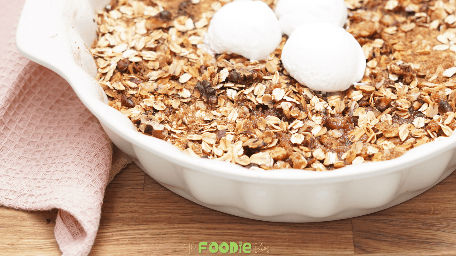 Close-up of healthy apple crisp baked in a white dish and topped with scoops of ice cream