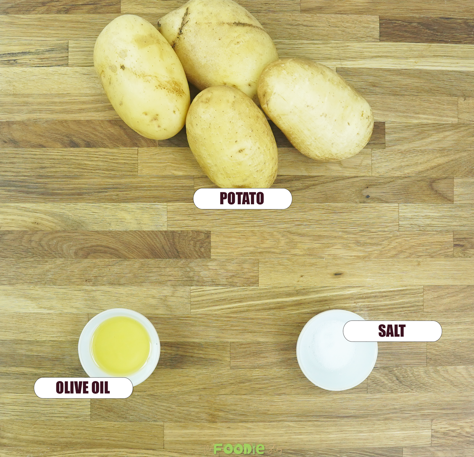 Ingredients for baked potatoes arranged on a wooden surface, including russet potatoes, olive oil, and salt.