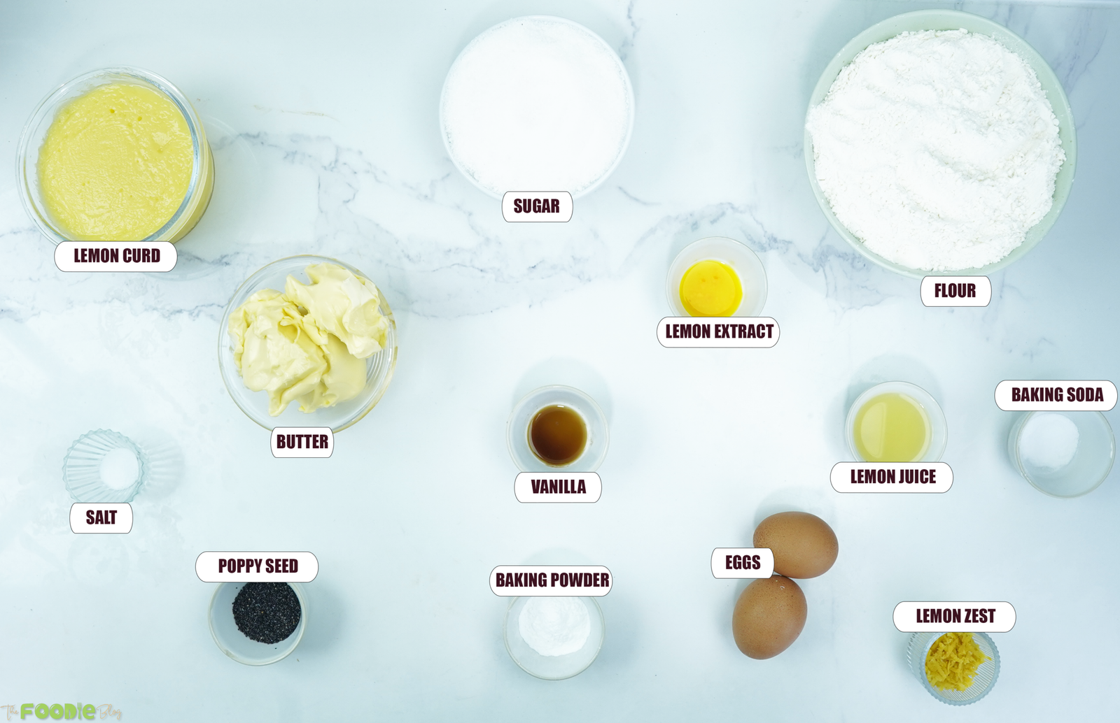 Ingredients for lemon poppy seed cookies arranged on a counter including butter, sugar, flour, eggs, lemon zest, lemon juice, lemon curd, poppy seeds, and baking staples