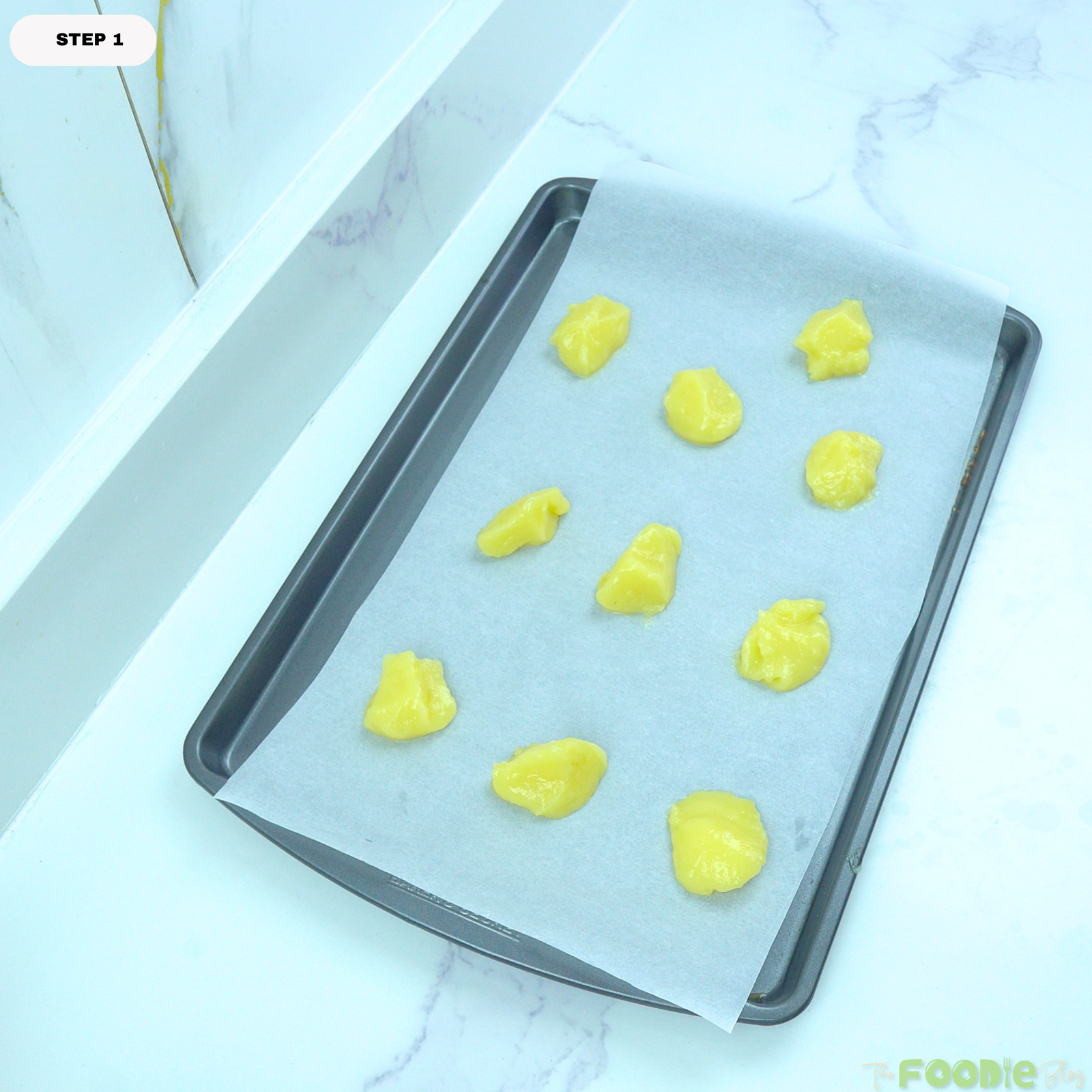 Small dollops of lemon curd placed on a parchment-lined baking sheet for lemon poppy seed cookies