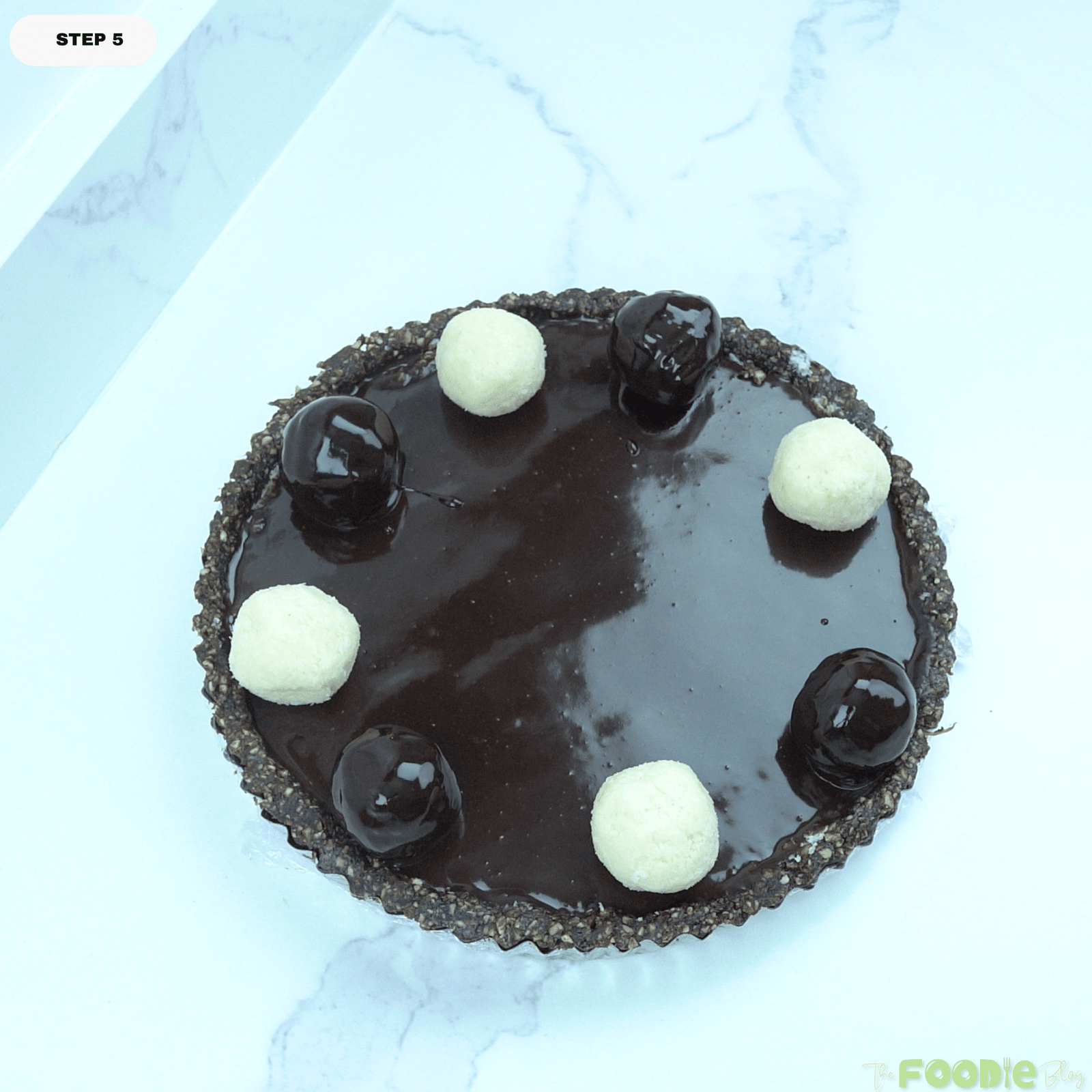 Top view of No-Bake Vegan Bounty Tart decorated with white coconut balls and chocolate-coated toppings