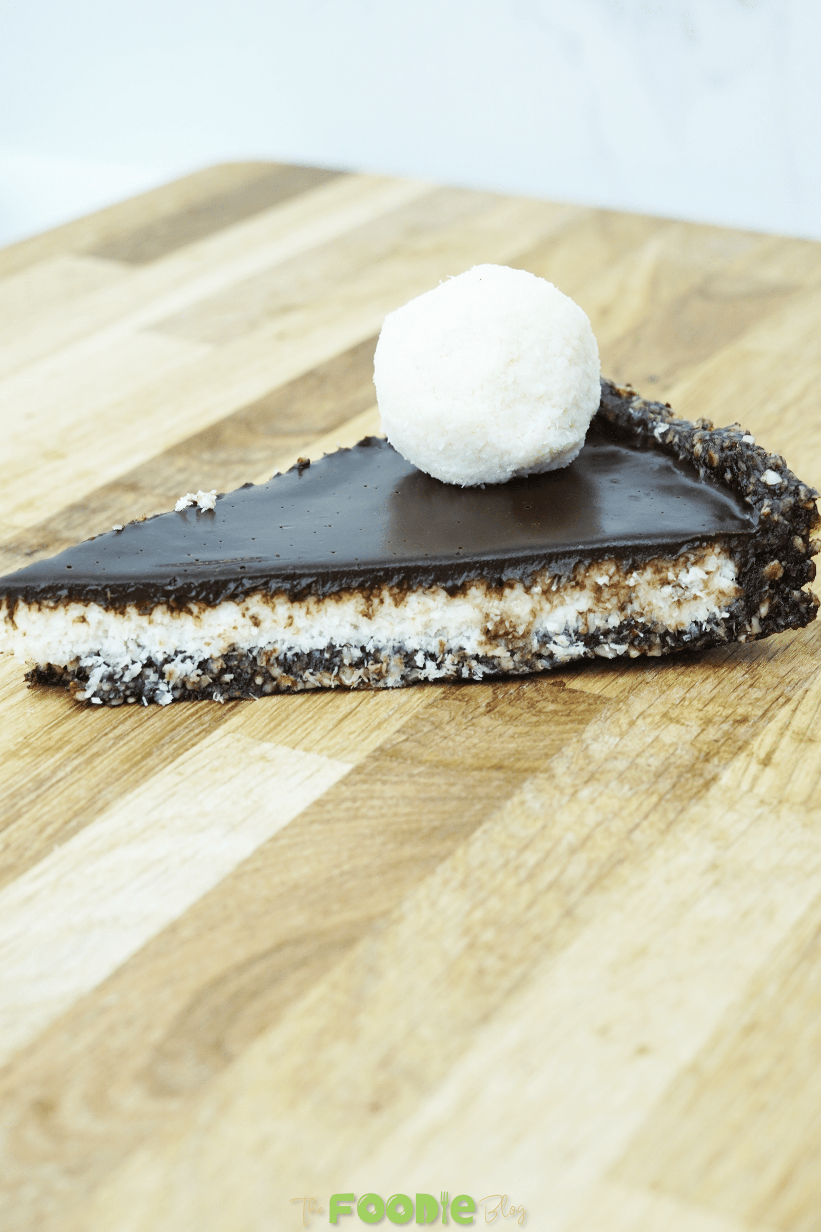 Overhead view of No-Bake Vegan Bounty Tart topped with coconut balls and chocolate-coated bites