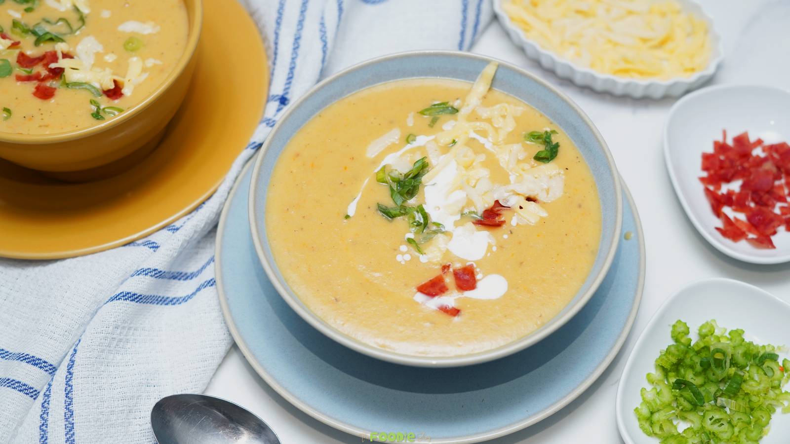 Bowl of creamy potato soup topped with shredded cheese, green onions, bacon bits, and a drizzle of sour cream