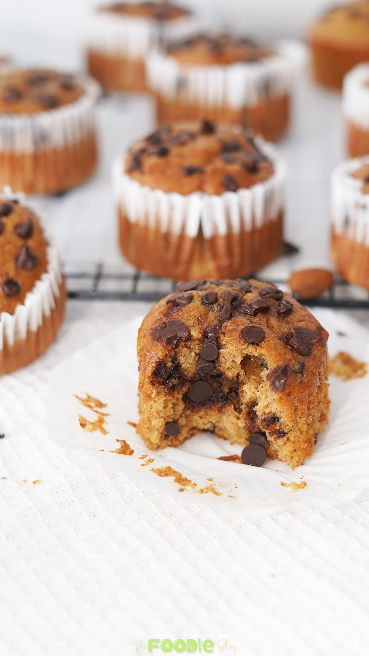 A bitten protein muffin with chocolate chips showing a soft banana almond butter crumb inside.