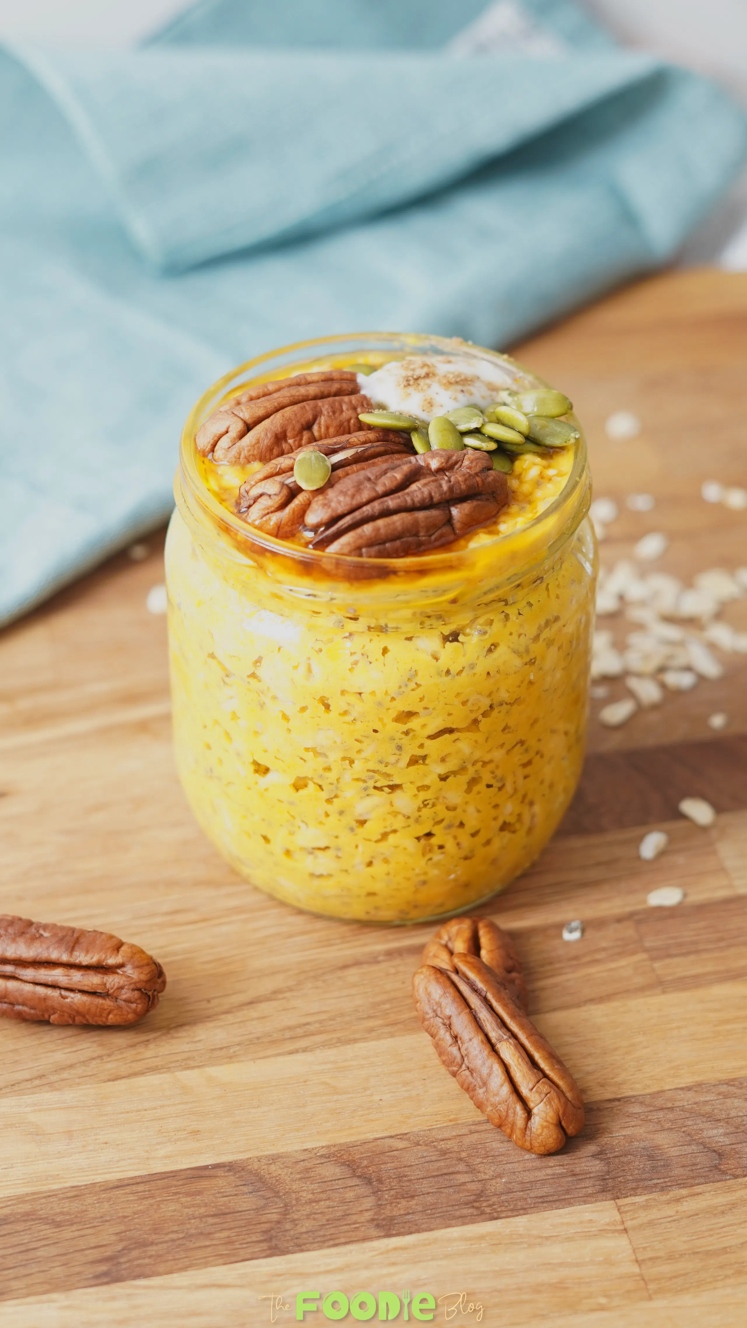 Close-up of a jar of pumpkin pie overnight oats with pecans, pumpkin seeds, and a creamy topping.