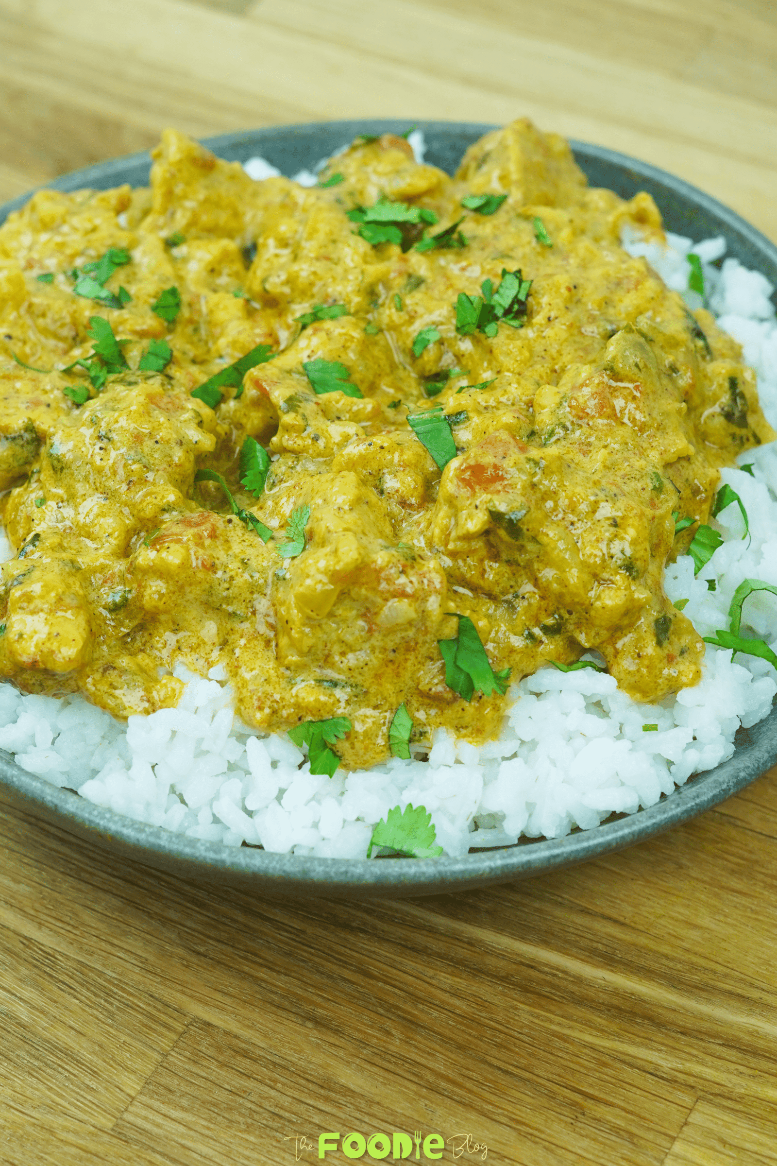 Close-up of creamy chicken curry with tomatoes and herbs served over white rice