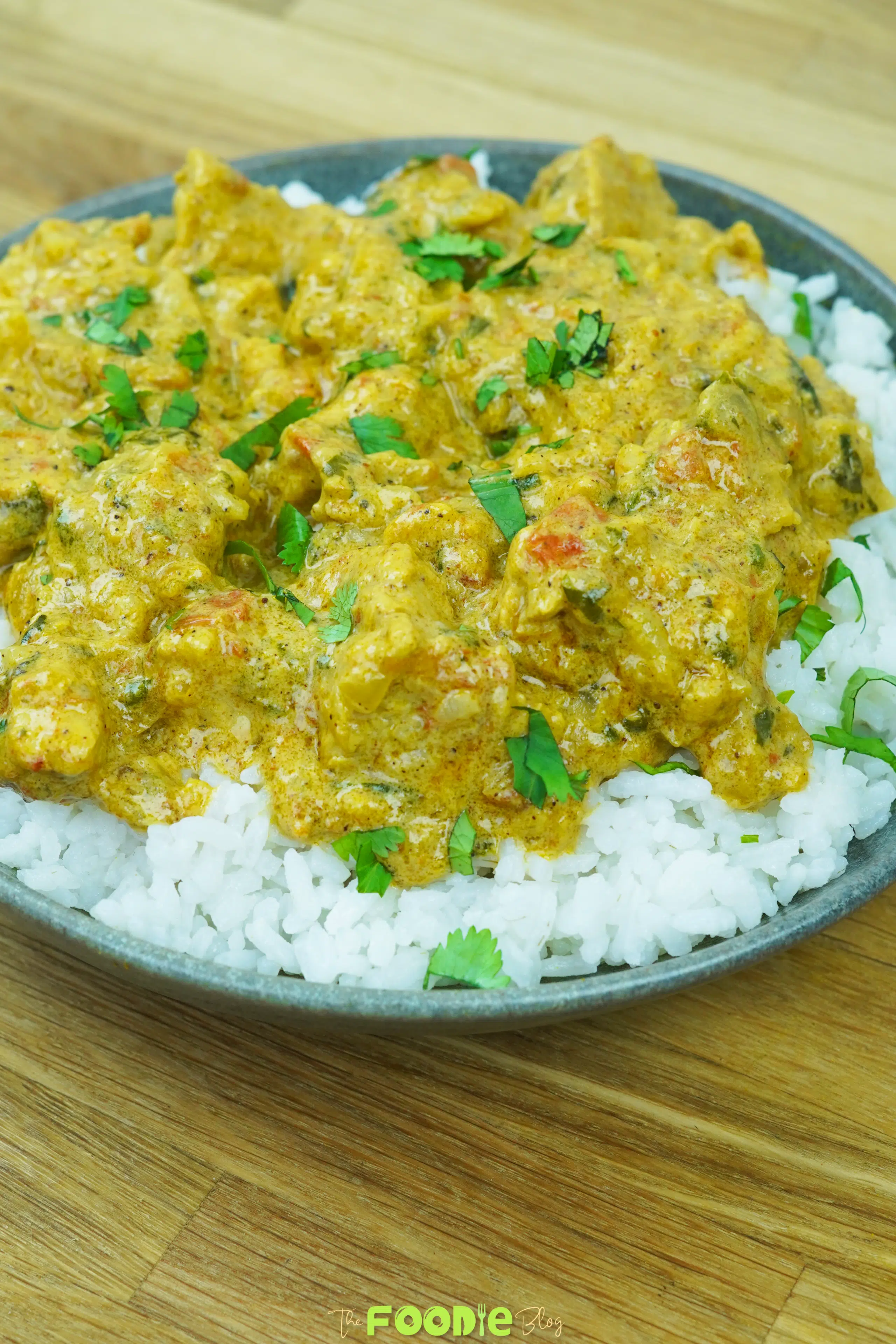Close-up of creamy chicken curry with tomatoes and herbs served over white rice