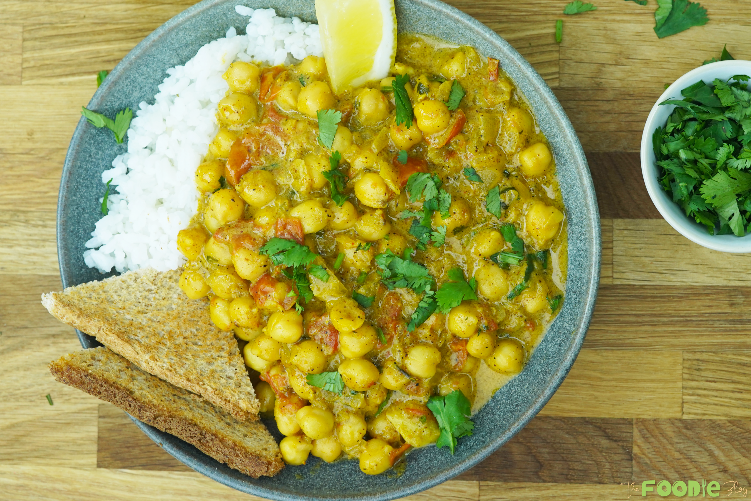 serving view of chickpea curry with rice, toast, and cilantro garnish