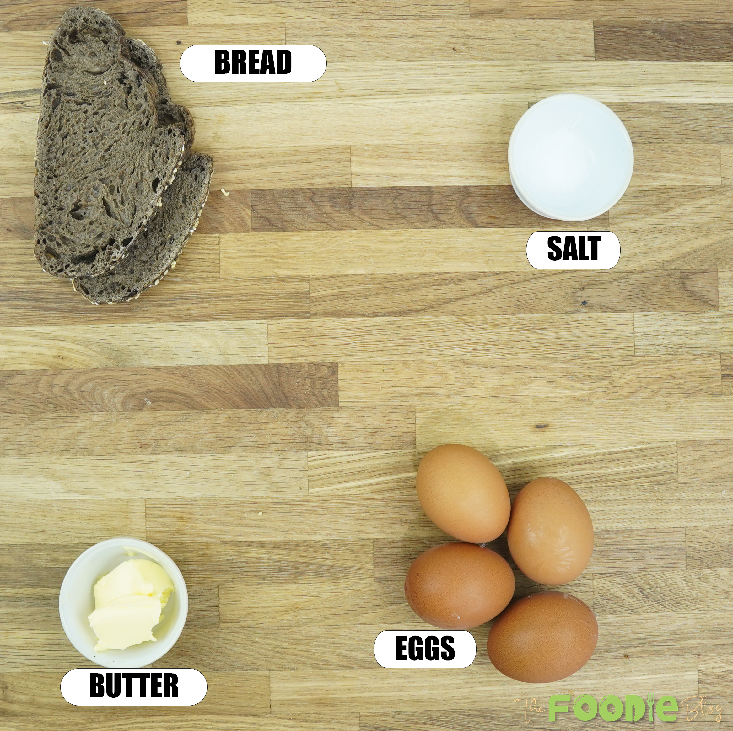 ingredients for scrambled eggs arranged on a wooden surface including eggs, bread, butter, and salt