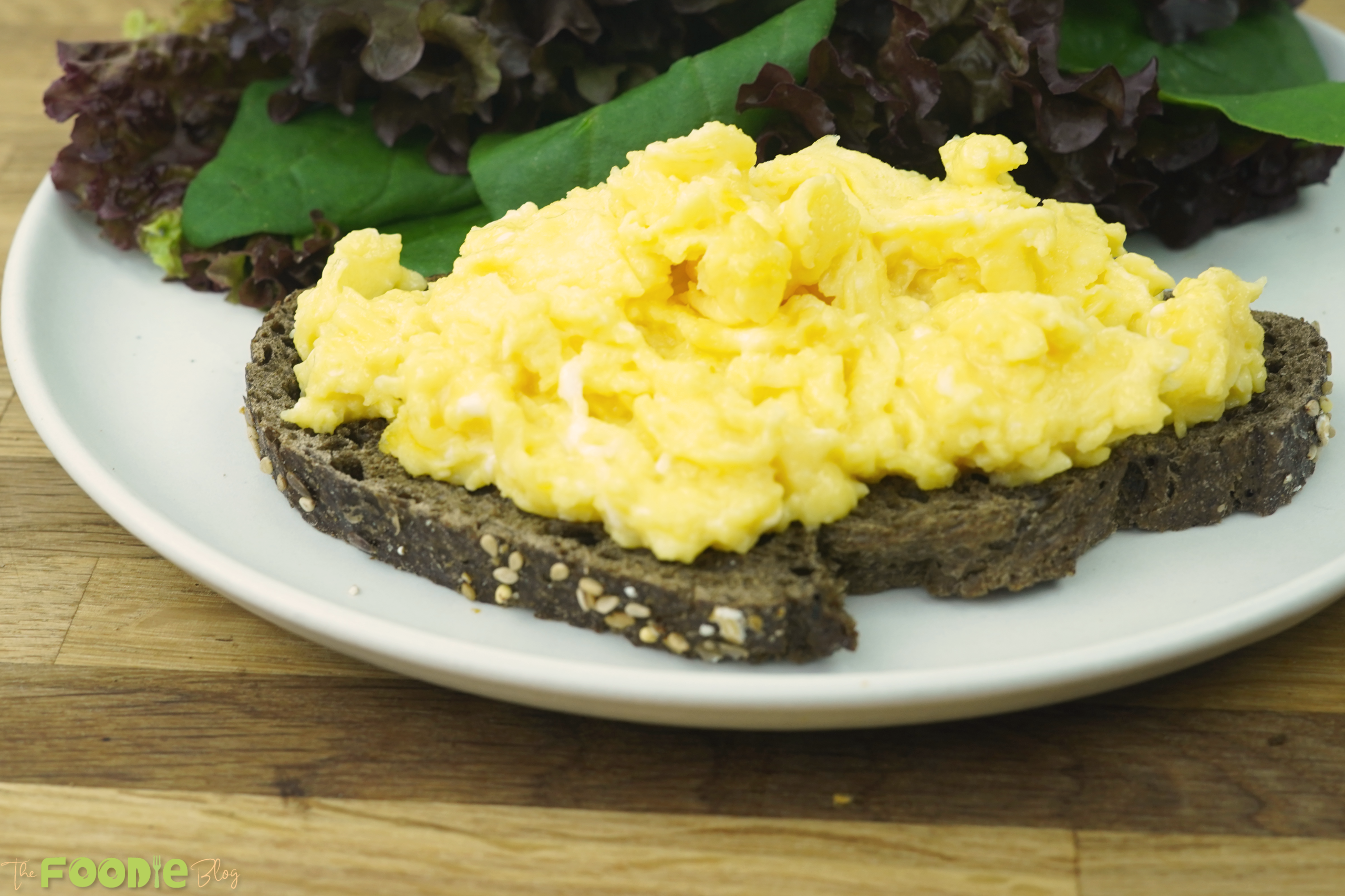 serving plate of scrambled eggs on toast with salad leaves