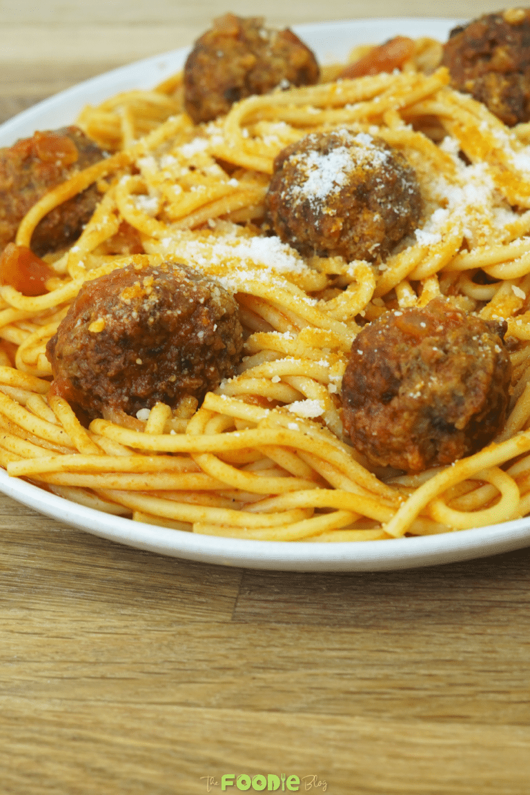 close-up of spaghetti and meatballs topped with grated Parmesan cheese