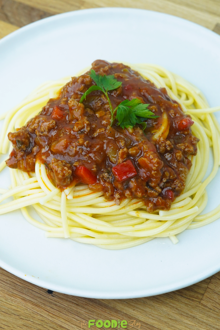 serving view of spaghetti with meat sauce on a white plate