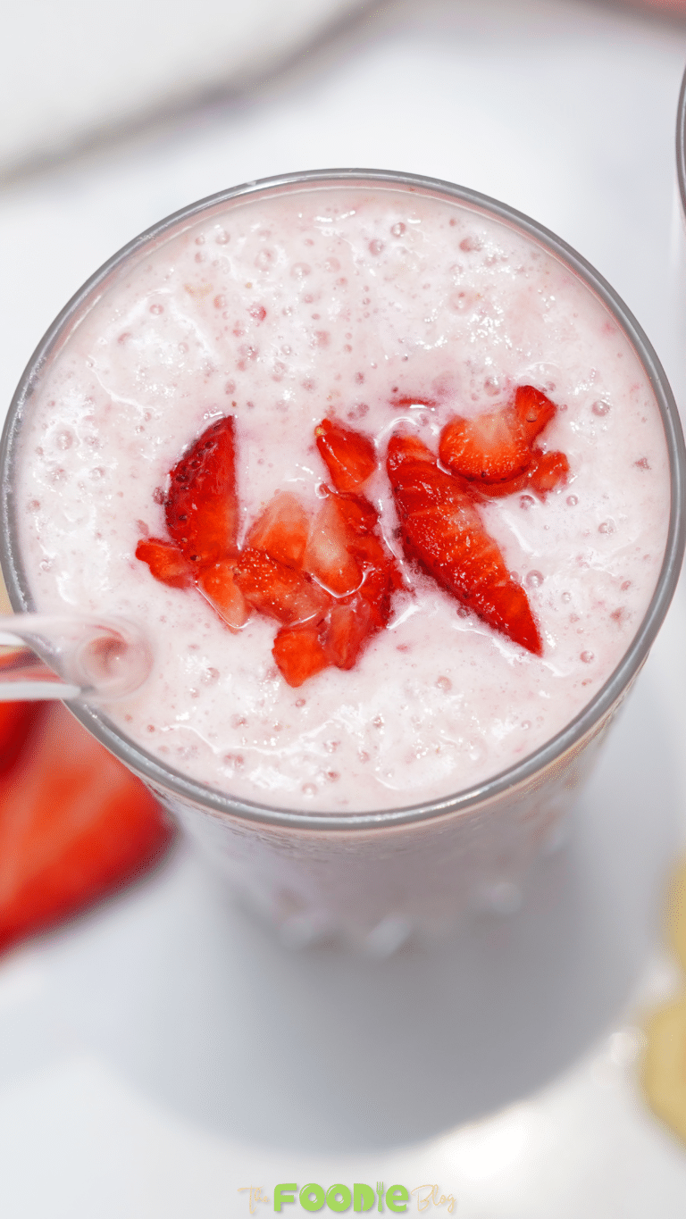 Close-up of a strawberry banana smoothie in a glass with chopped strawberries on top