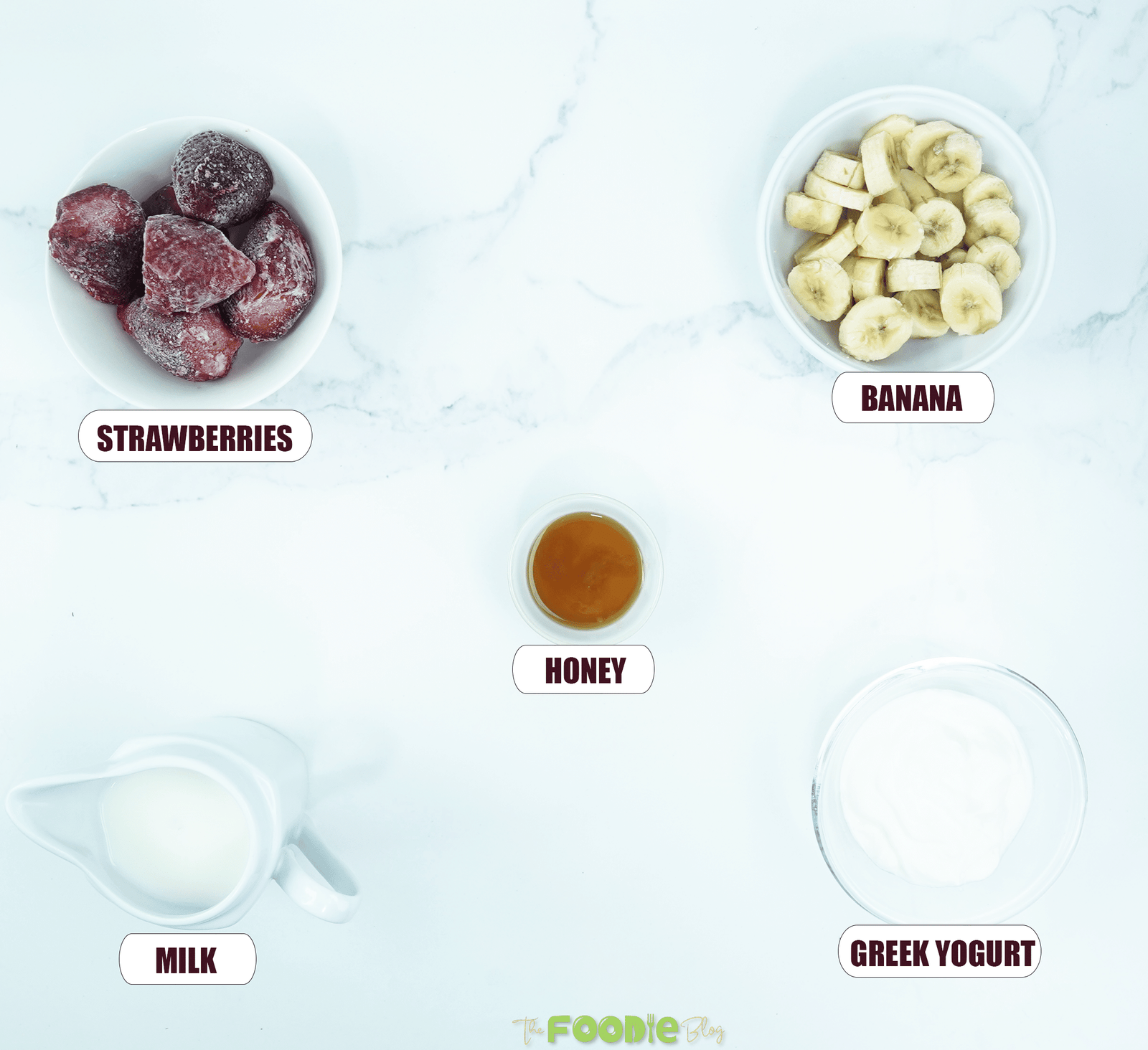 Ingredients for strawberry banana smoothie including strawberries, banana, honey, milk, and Greek yogurt arranged on a light surface
