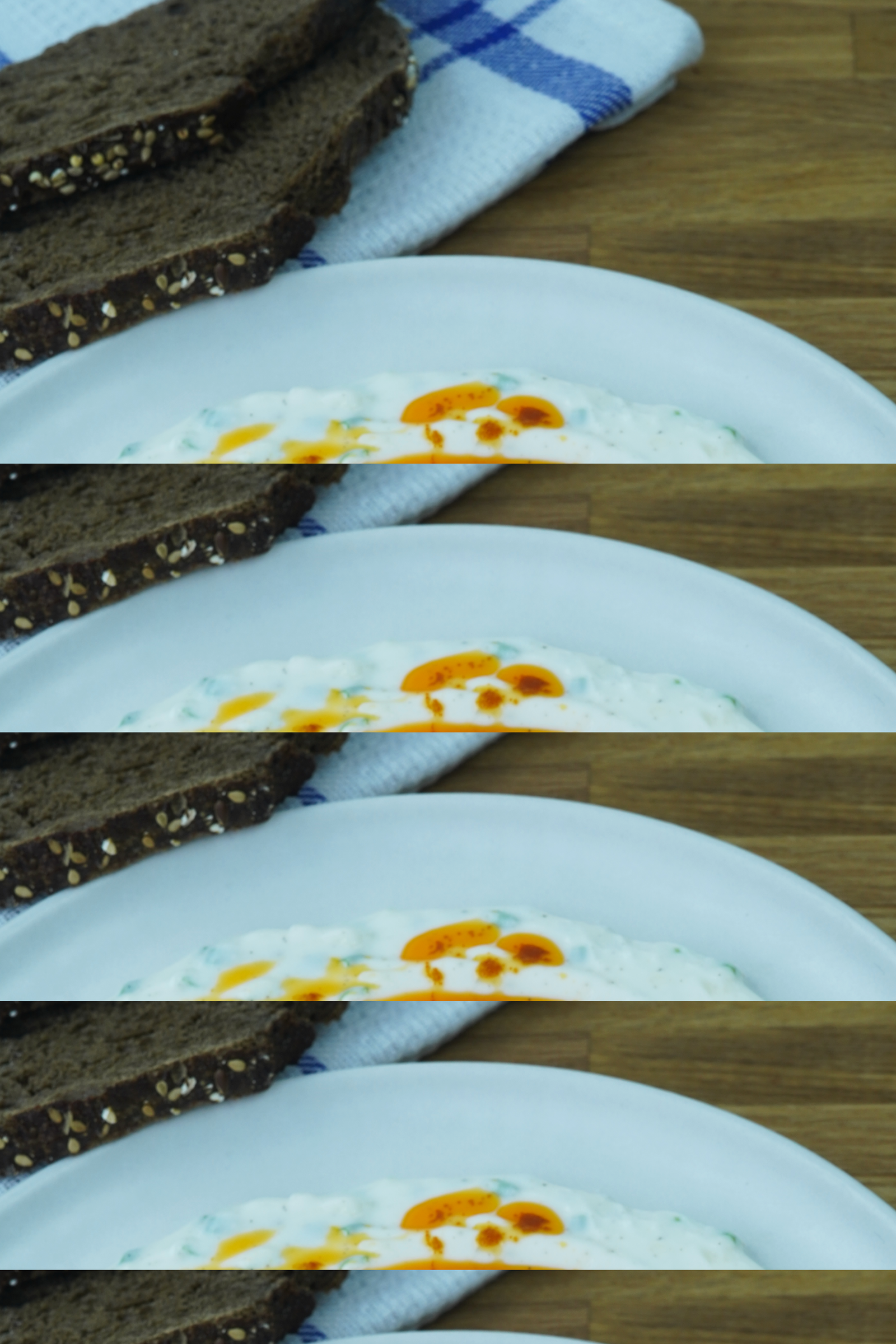 Turkish eggs served on a white plate with poached eggs, garlicky yogurt, paprika butter, and toasted bread in the background