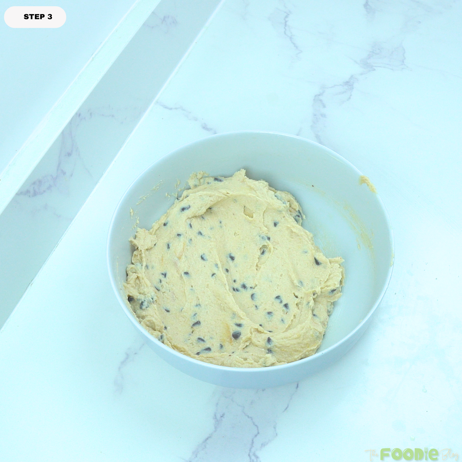 Finished cottage cheese cookie dough with chocolate chips mixed in, spread inside a white mixing bowl.