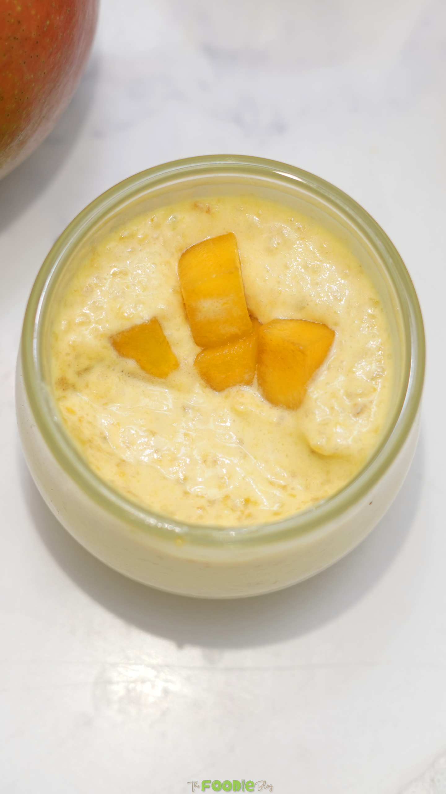 Creamy mango mousse served in a small glass jar with diced mango on top.