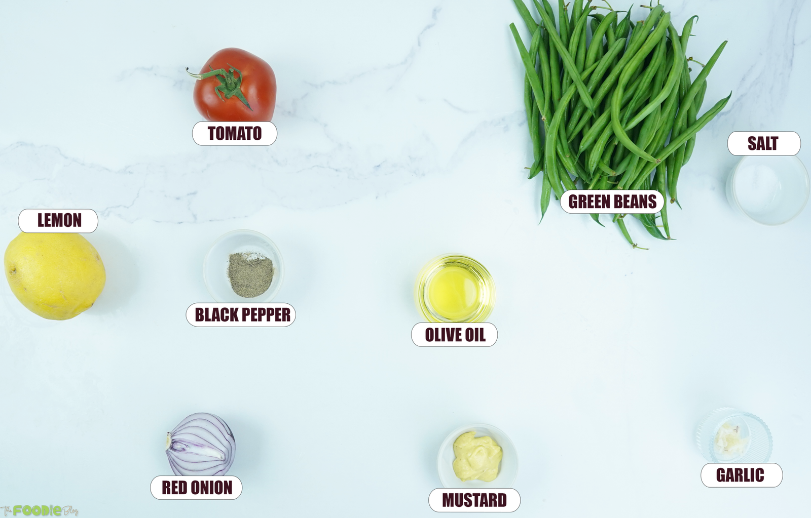 Ingredients for green bean salad including fresh green beans, tomato, red onion, lemon, olive oil, Dijon mustard, garlic, salt, and black pepper.
