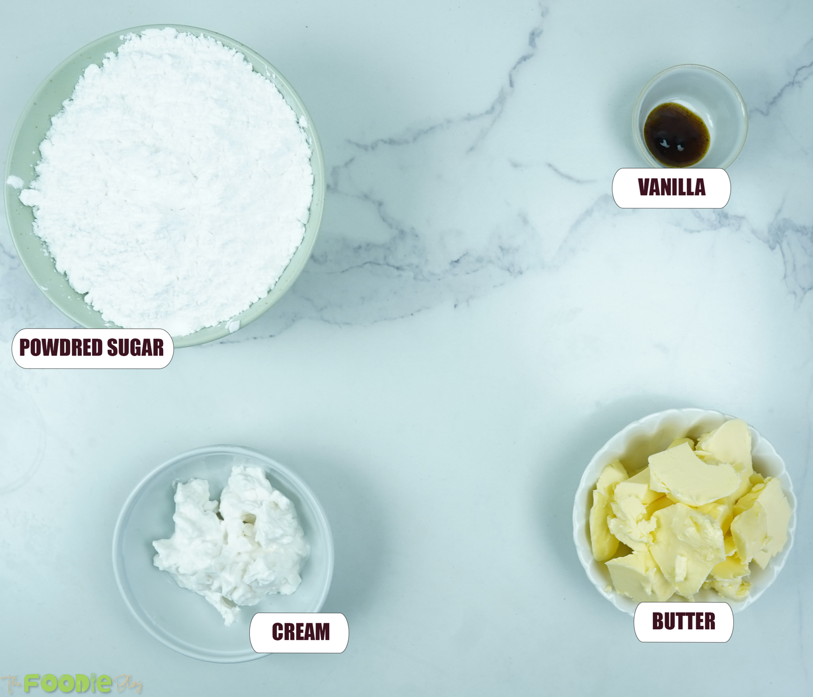Powdered sugar, vanilla, cream, and butter arranged for making vanilla buttercream frosting.