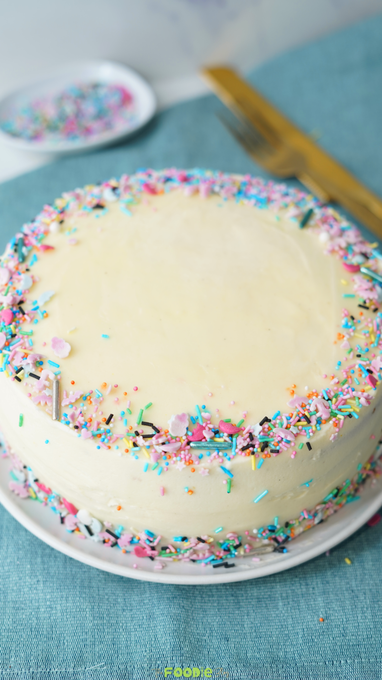 homemade fluffy vanilla cake with vanilla frosting and rainbow sprinkles