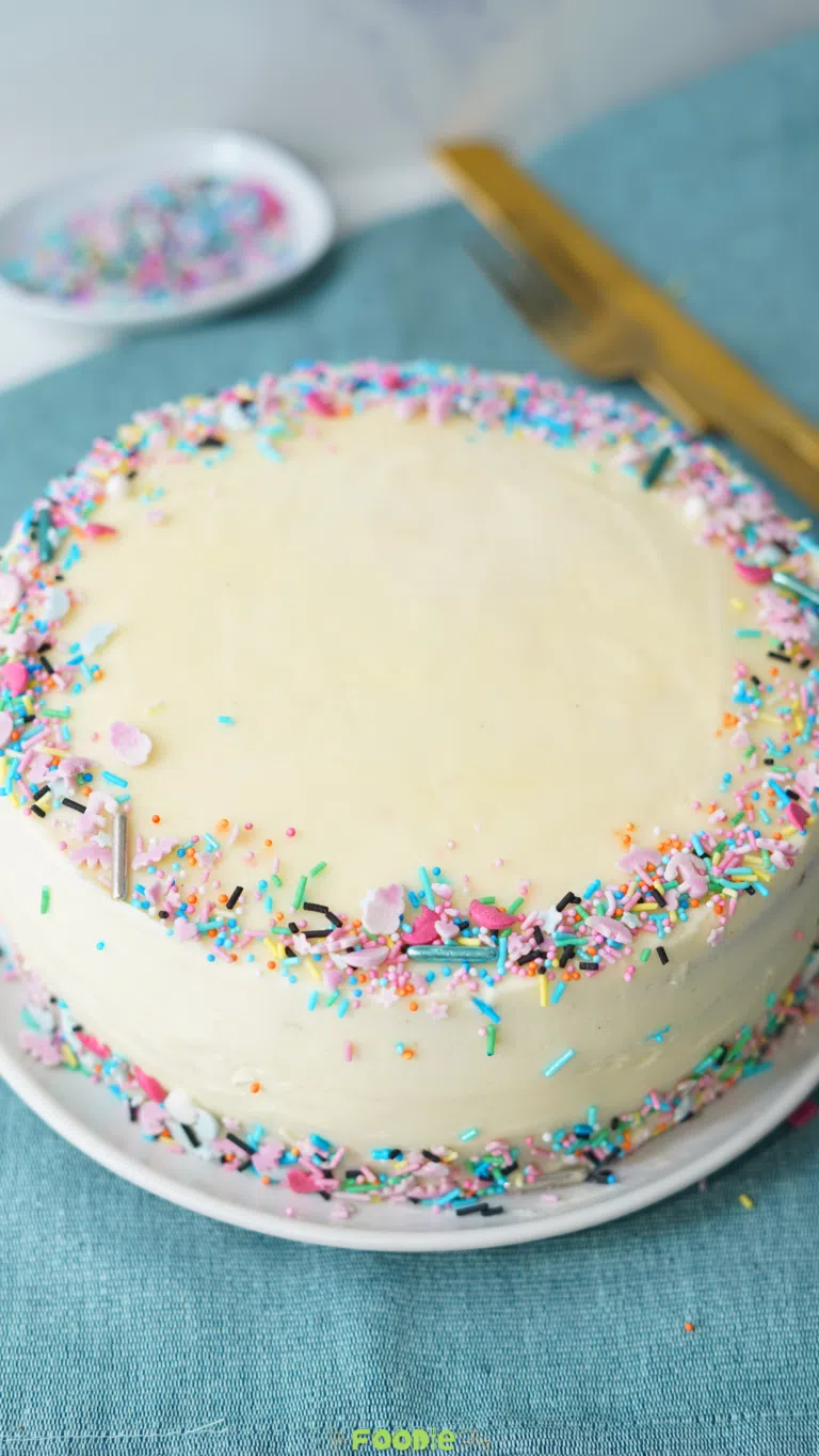 homemade fluffy vanilla cake with vanilla frosting and rainbow sprinkles