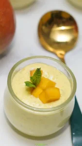 Creamy mango mousse in a glass jar topped with diced mango and fresh mint.