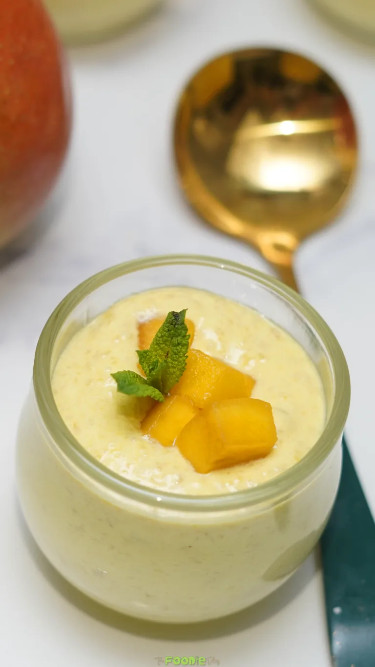 Creamy mango mousse in a glass jar topped with diced mango and fresh mint.