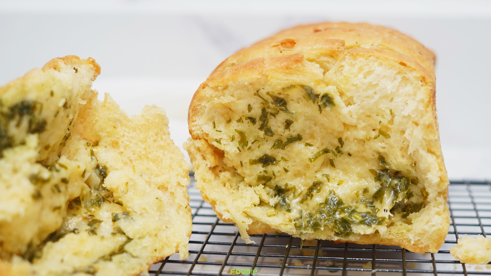 Close-up of soft sourdough pull apart bread with a buttery garlic herb filling inside.