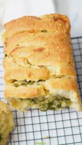 Golden baked sourdough pull apart bread resting on a cooling rack.