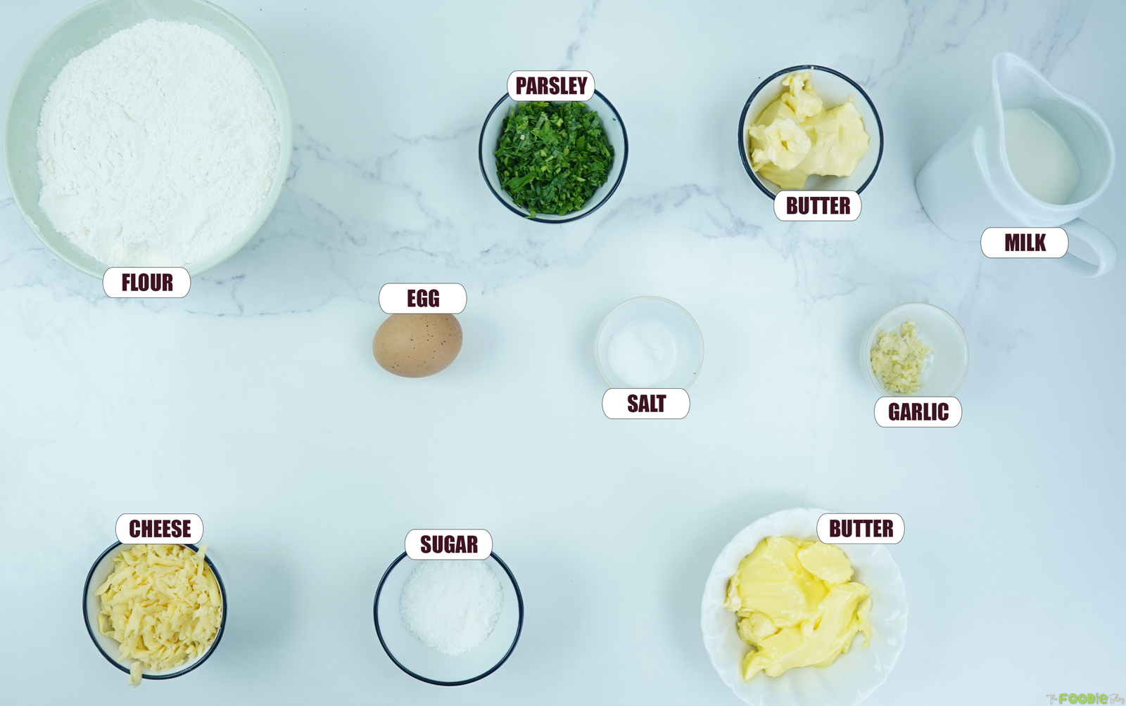 Ingredients for sourdough pull apart bread including flour, parsley, butter, milk, egg, garlic, cheese, sugar, and salt.