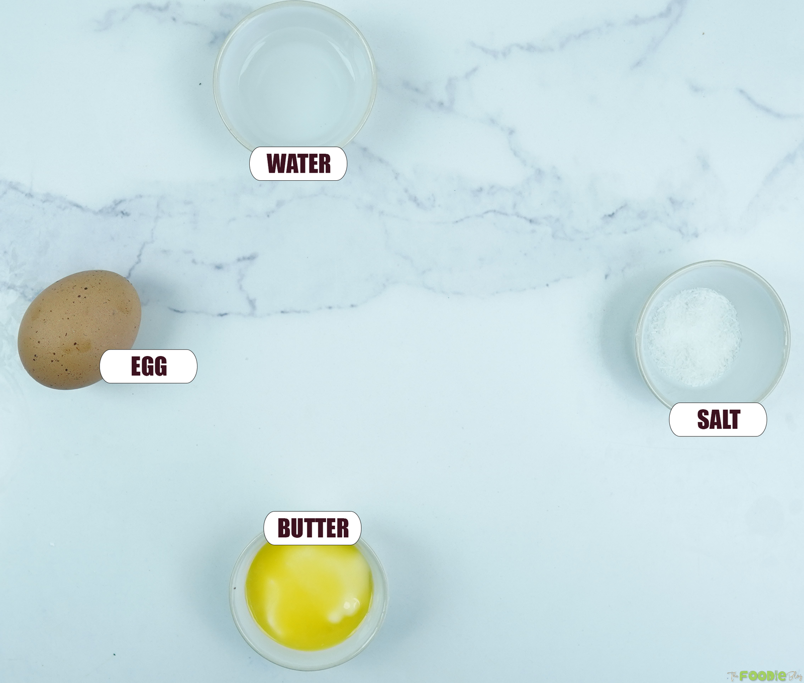Ingredients for the sourdough starter build including egg, melted butter, water, and salt arranged overhead.