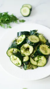 Chunky smashed cucumber salad with cilantro and sesame ginger dressing on a white plate.