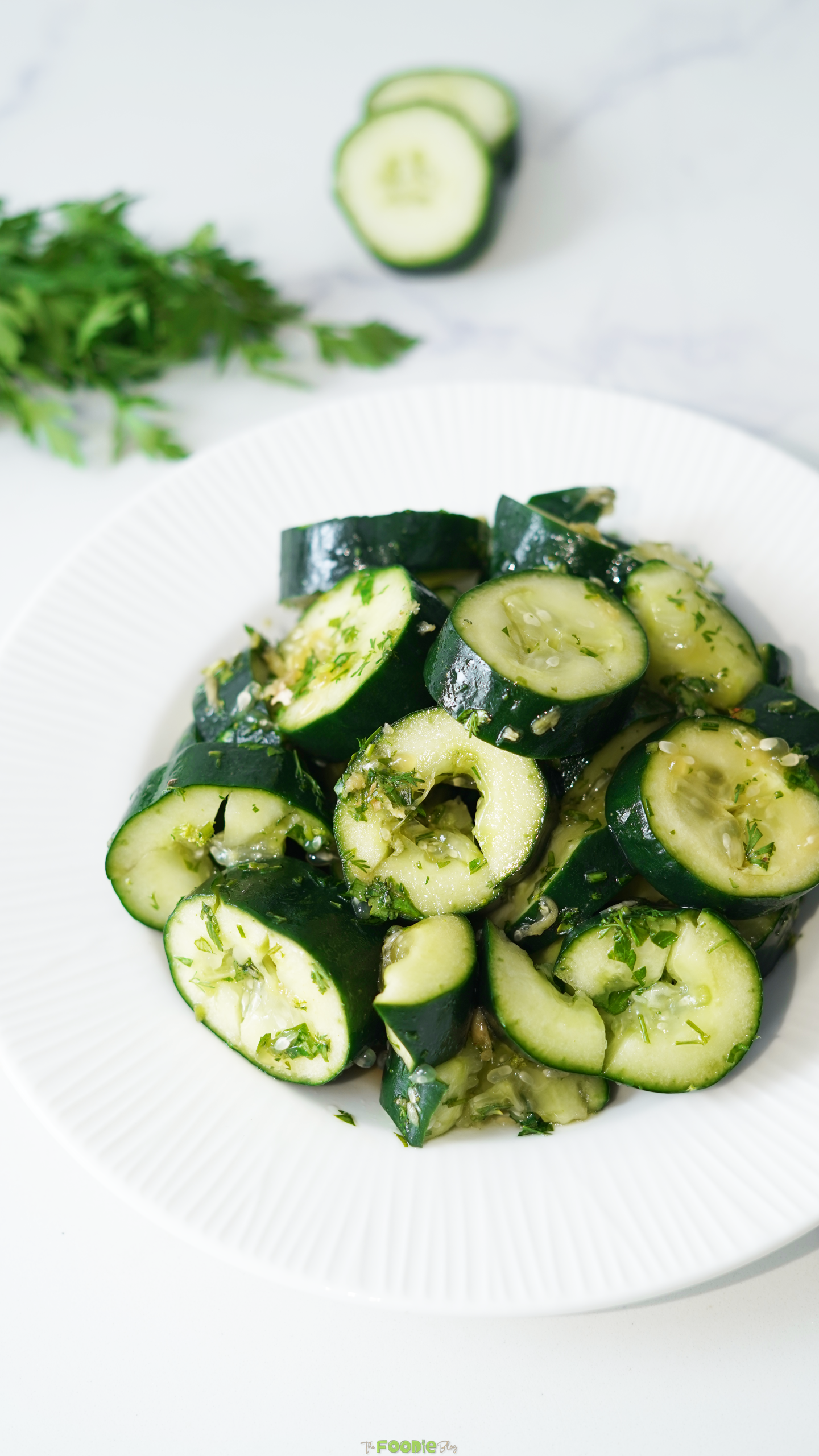 Chunky smashed cucumber salad with cilantro and sesame ginger dressing on a white plate.