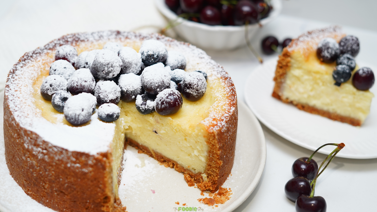 Classic baked cheesecake with a slice served on a plate and fresh berries on top.
