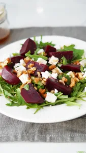 Close-up of beetroot salad with arugula, feta cheese, and walnuts.