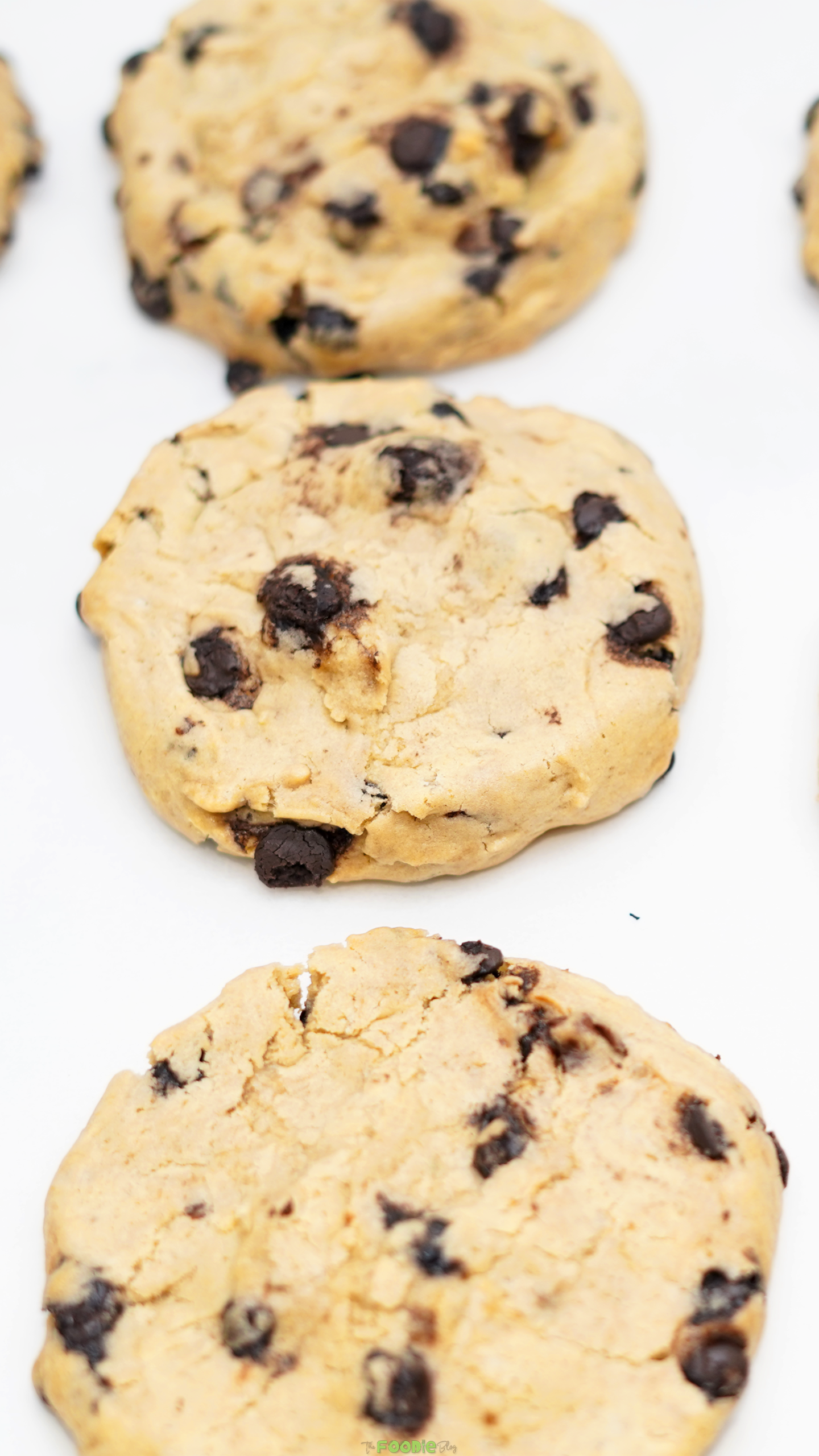 Close-up view of thick chocolate chip cookies with lightly golden tops and dark chocolate pieces.