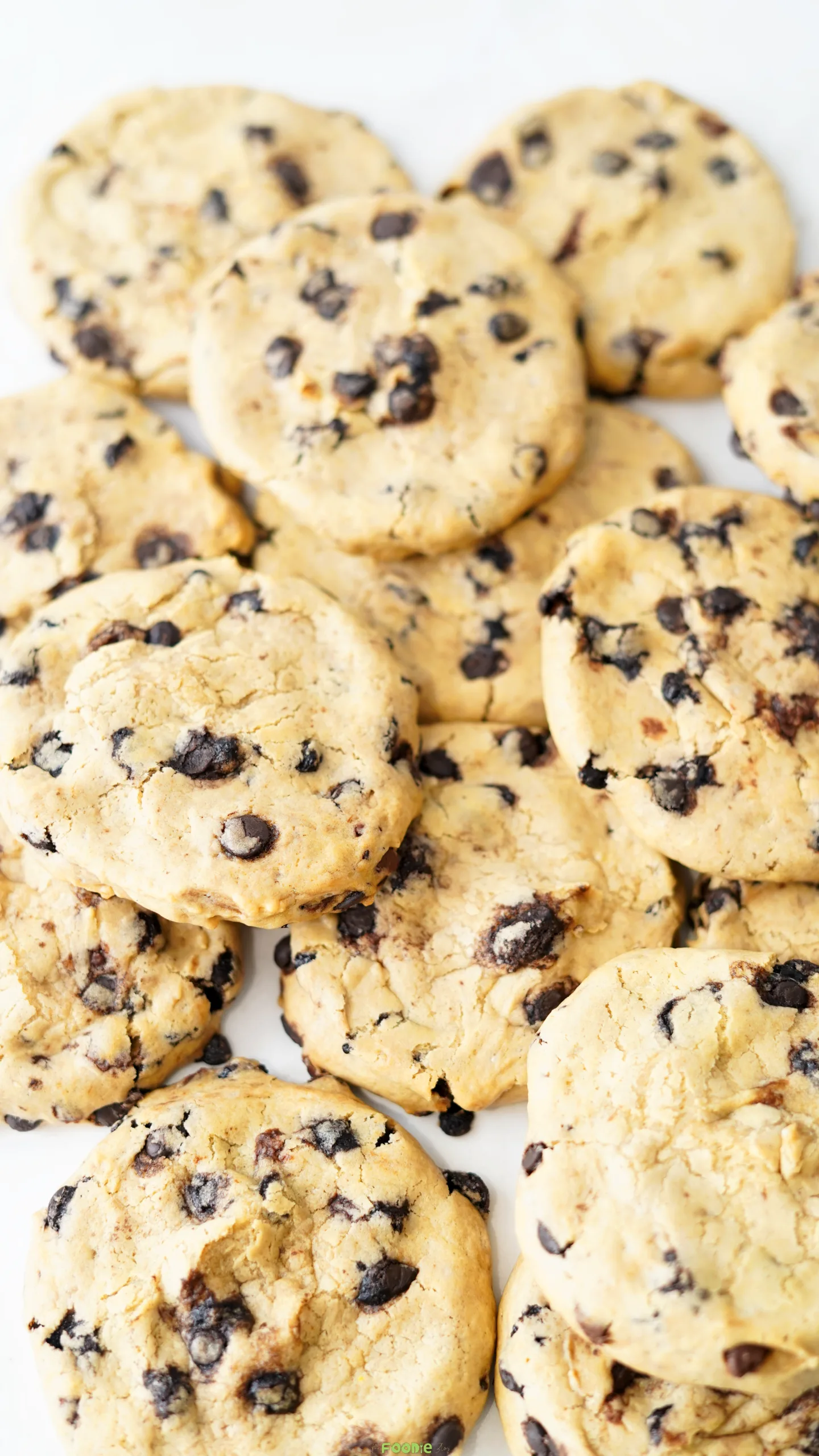 Close-up of soft chocolate chip cookies stacked together with chocolate chips and chopped chocolate pieces.