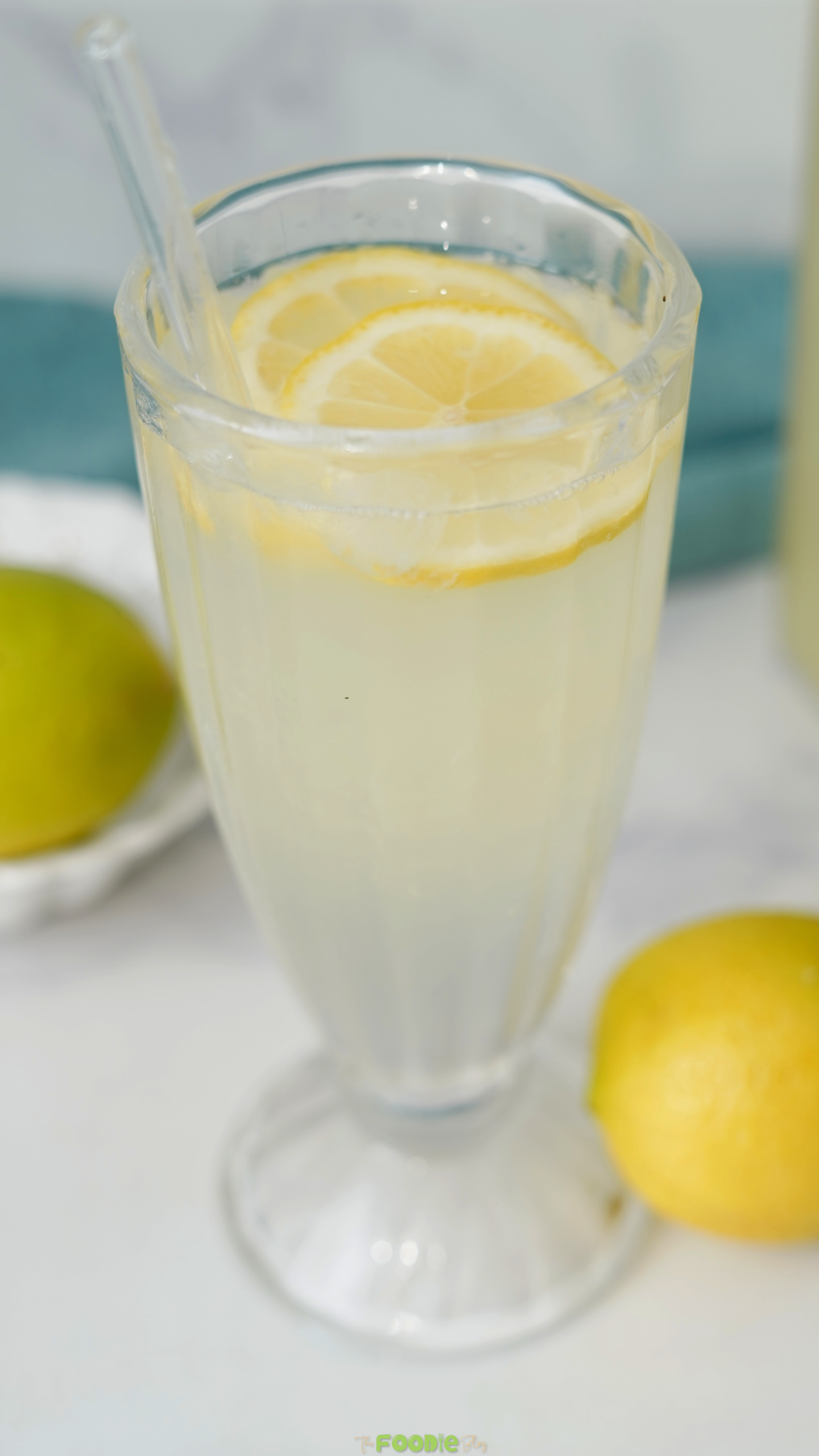 Tall glass of homemade lemonade with lemon slices and a straw.