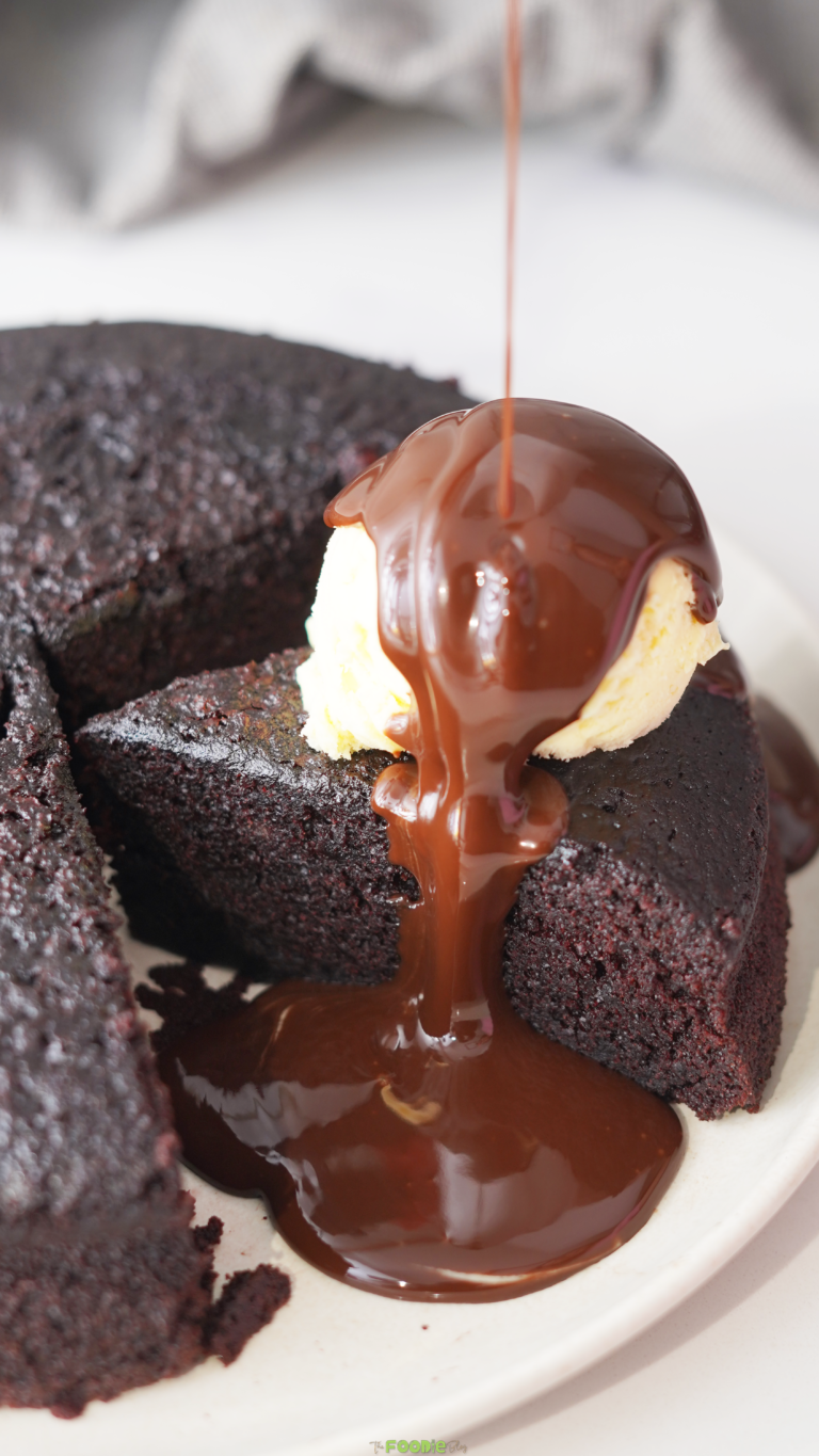 Chocolate sauce pouring over vanilla ice cream on a warm chocolate cake slice.