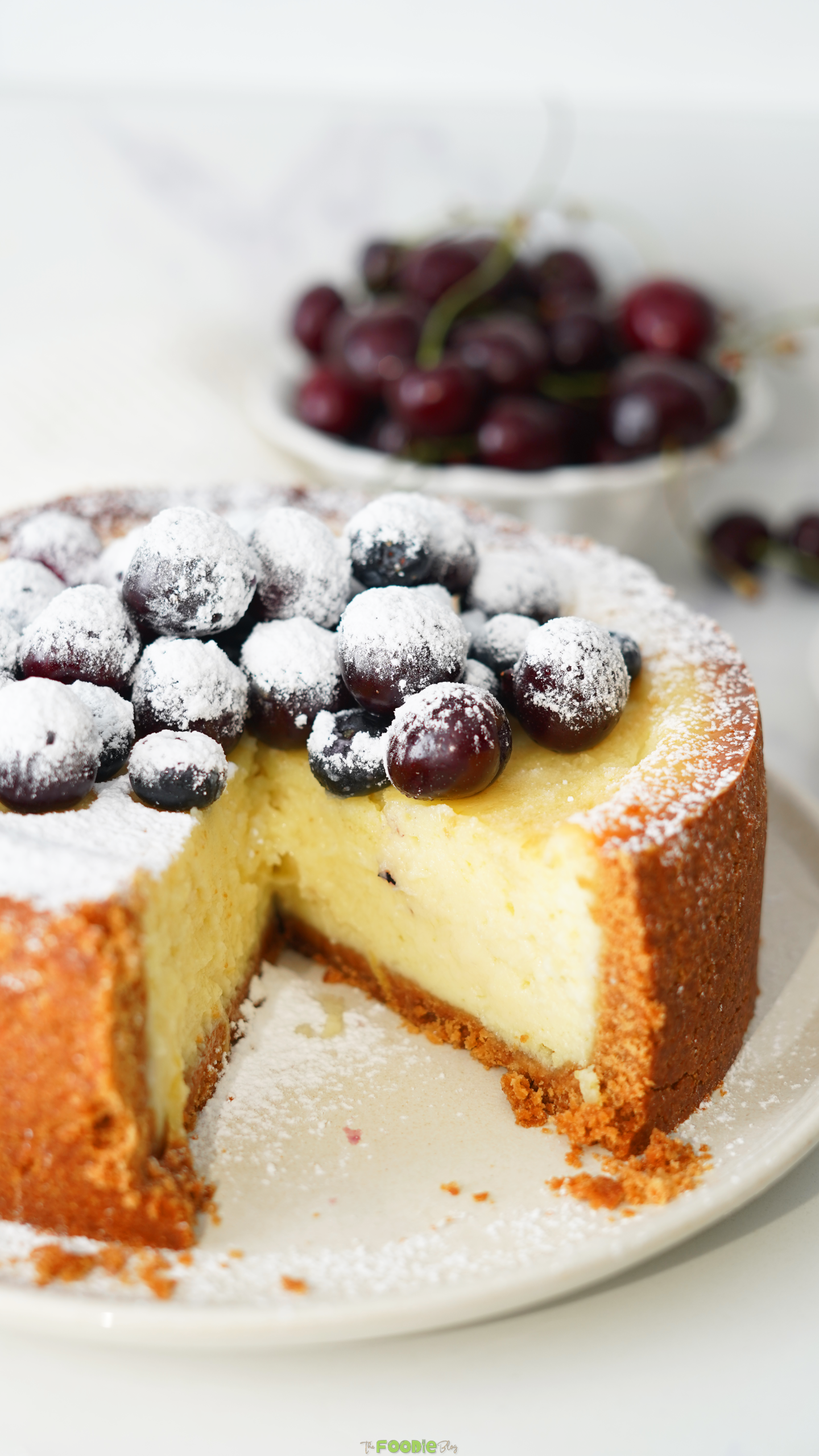 Close-up of creamy baked cheesecake topped with powdered sugar and dark berries.