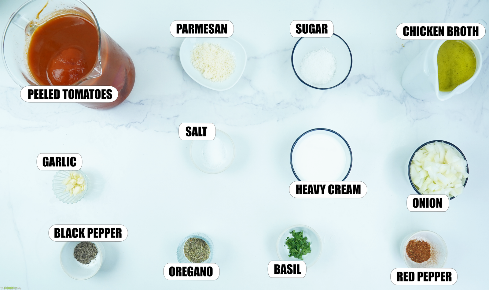 Ingredients for Creamy Tomato Soup including peeled tomatoes, garlic, onion, chicken broth, heavy cream, parmesan, basil, oregano, sugar, salt, black pepper, and red pepper flakes.